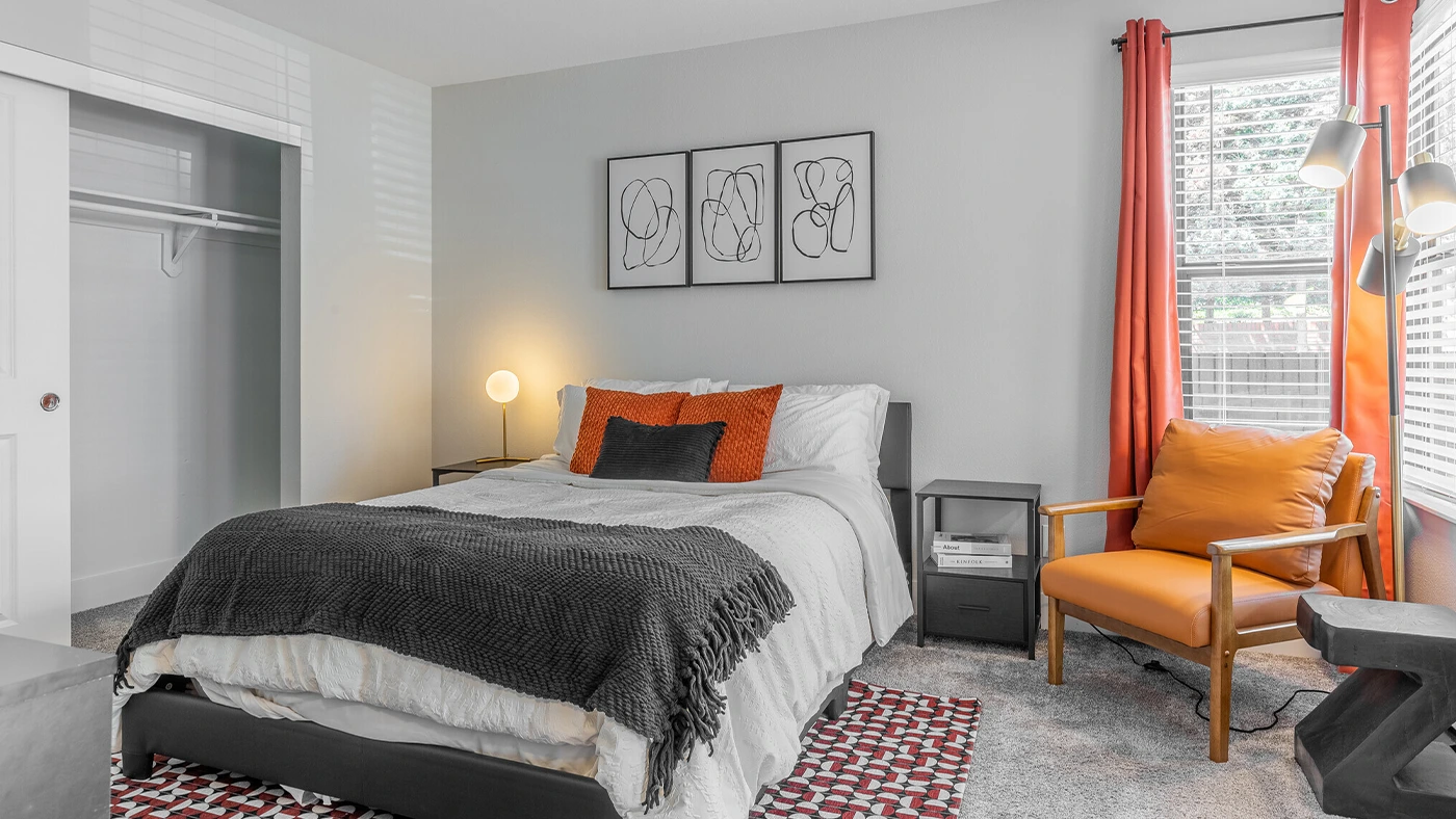Cozy modern bedroom with stylish furniture, vibrant orange accents, and a serene atmosphere.