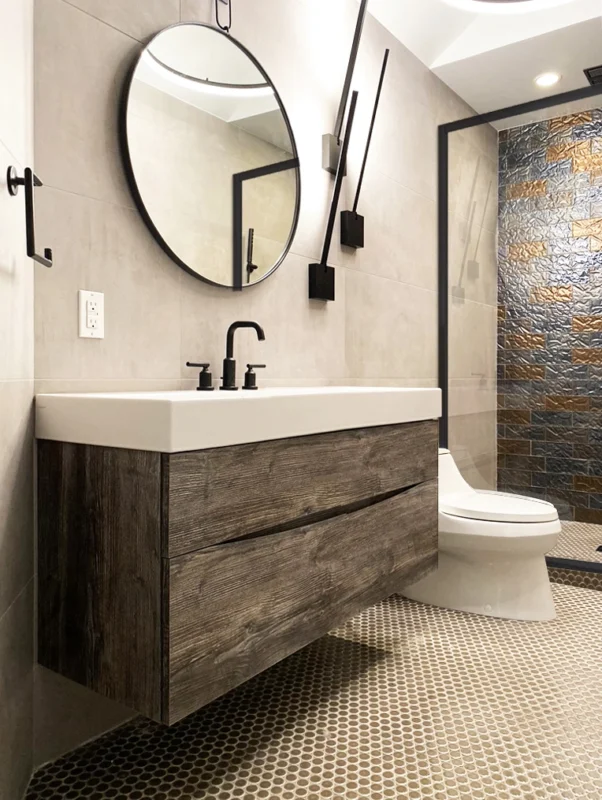 Modern bathroom design featuring a floating vanity, circular mirror, and stylish mosaic tile flooring.