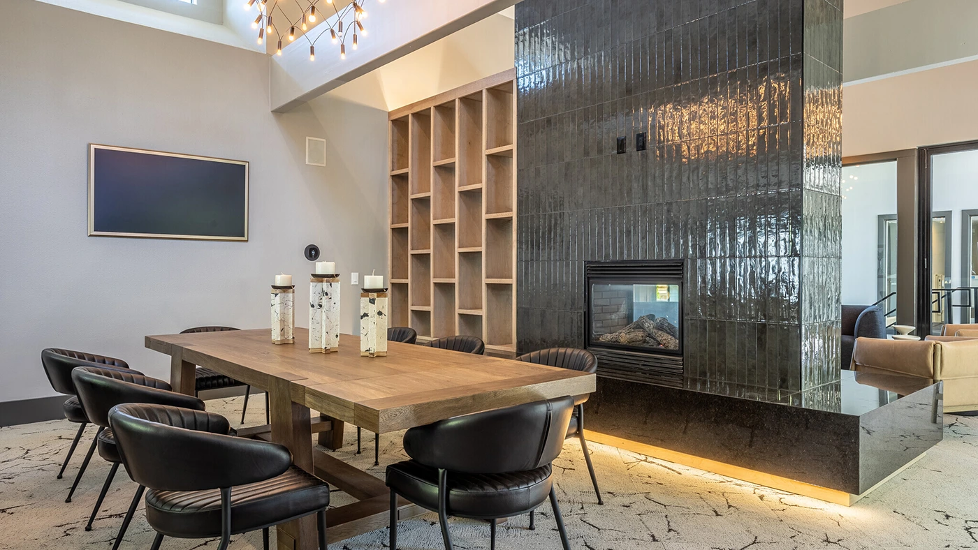 Elegant modern dining lounge with wooden table, black chairs, and stylish fireplace design.