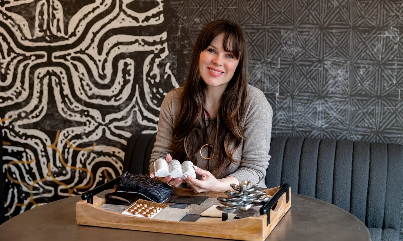 Woman at a table showcasing her design creativity in a modern, stylish setting.