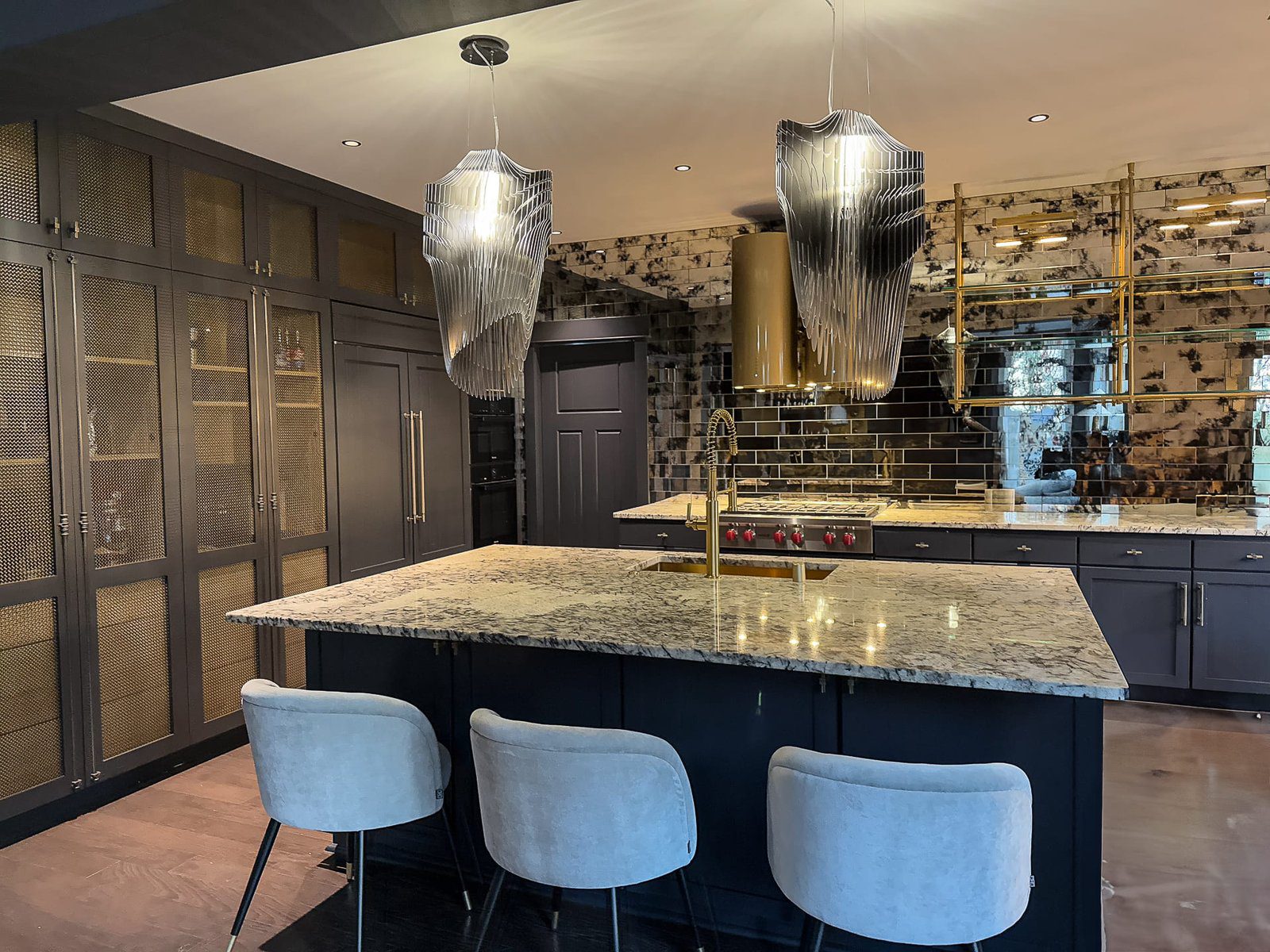 Elegant modern navy blue kitchen with granite island and stylish lighting.